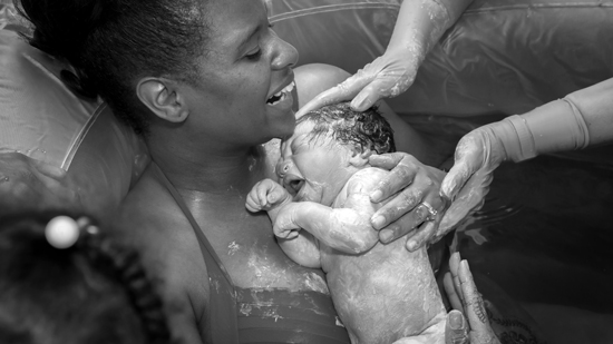 smiling woman straight after water birth with new born baby