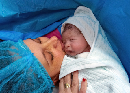 new born baby being held close to mother after c-section delivery